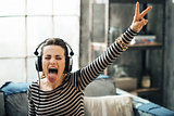 Cheerful young woman listening to music in loft apartment