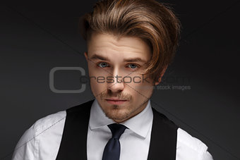 Handsome young gentelman wearing elegant white shirt  and black suit posing on camera.