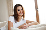 Young smiling lady with beautiful make-up sitting and relaxing on the sofa.
