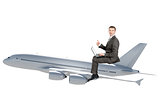 Businessman with laptop flying on jet