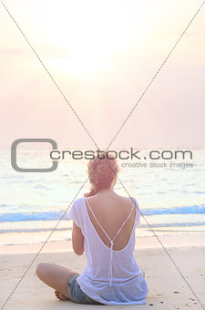 woman practicing yoga at sunrise beach
