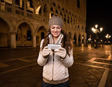 Smiling woman tourist writing sms on St. Mark's Square, Venice