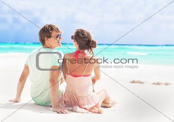back view of couple sitting on a tropical beach in Barbados