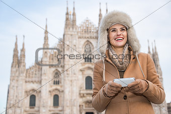 Happy woman writing sms on smartphone while standing near Duomo