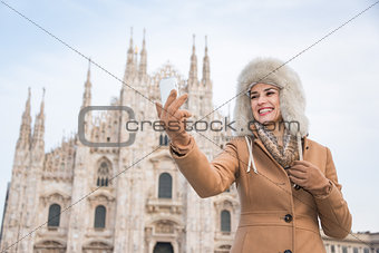 Smiling woman traveller taking selfie with smartphone in Milan