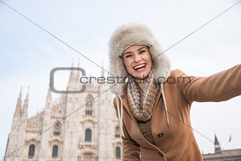 Happy woman tourist taking selfie in the front of Duomo, Milan