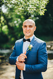 Groom in a blue suit buttoning cuffs