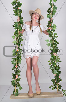 girl in little dress and cowboy hat on a swing