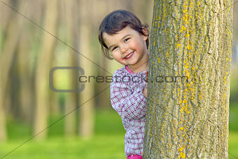 Little girl hiding behind a tree