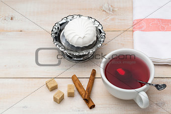 Cup of red tea. Cane sugar and cinnamon sticks with sweet dessert