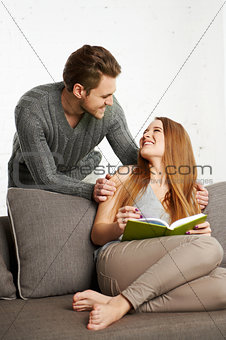 Happy young couple is relaxing on sofa in living room.