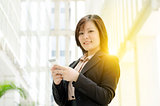 Young Asian business woman texting on smartphone