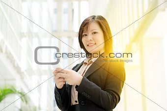 Young Asian business woman texting on smartphone