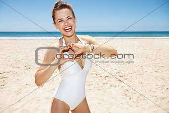 Happy woman in swimsuit showing heart shaped hands at sunny day