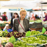 Woman buying vegetable at local food market.