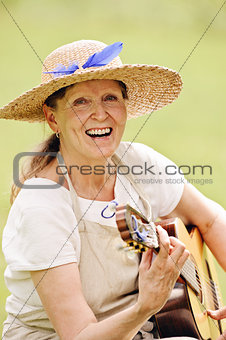 senior woman playing guitar outdoors