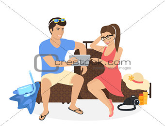 Young couple sitting on the luggage and using tablet pc to watch photos from their holiday