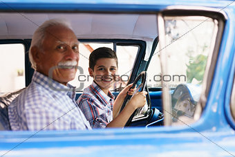 Portrait Grandpa Giving Driving Lesson To Boy In Old Car