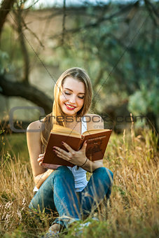 Beautiful girl reading a book on the Nature