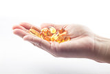 Hand holding fish oil capsules on white background