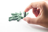 Hand hoding green capsule pills on white background