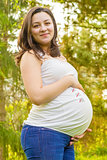 portrait of pregnant young woman outdoors in warm summer day