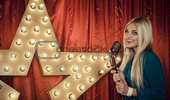 Beautiful woman singing on stage with microphone