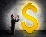 Businessman on knees in front of dollar sign