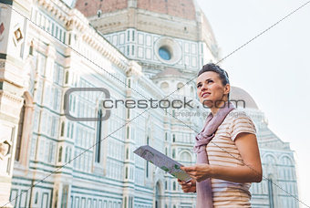 Happy woman with tourist map looking into distance in Florence