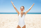 Happy woman in swimsuit at sandy beach on sunny day rejoicing