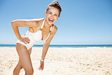 Portrait of happy woman in white swimsuit at sandy beach