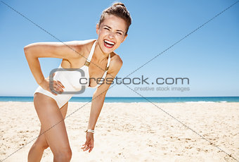 Portrait of happy woman in white swimsuit at sandy beach
