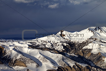 Winter mountains at sun evening and dark clouds
