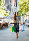 Happy woman with shopping bags walking near Sagrada Familia