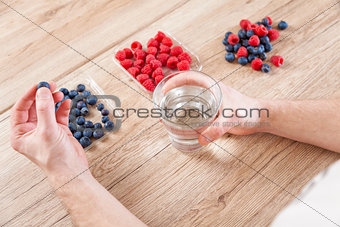 Closeup on man with a glass of water healthy berries on table