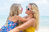Cute girl and beautiful mother on the beach