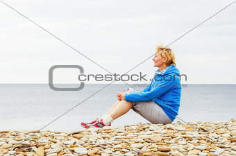 Woman sitting on the beach and looks into the distance