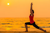 woman engaged in yoga at sunset near the ocean