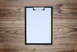 Blank white paper sheet A4 on clipboard. Wooden background.