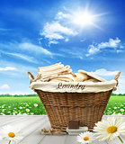 Laundry basket with clothes on rustic table against blue sky