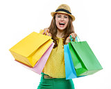 Woman in hat and bright clothes with shopping bags rejoicing
