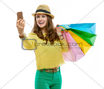 Woman in hat and bright clothes with shopping bags taking selfie