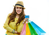 Happy woman in hat with shopping bags showing credit card