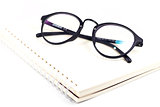 Blank spiral notebook and eyeglasses isolated on white backgroun