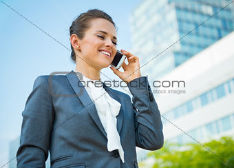 Smiling business woman in office district talking mobile phone