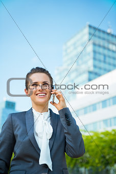Happy business woman in modern office district talking cellphone