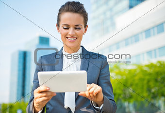 Smiling business woman using tablet PC in modern office district