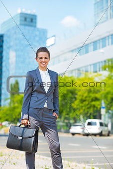Happy business woman with briefcase in modern office district