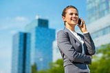 Smiling business woman in office district talking cellphone
