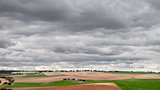 Green cultivated fields against cloudy stormy sky